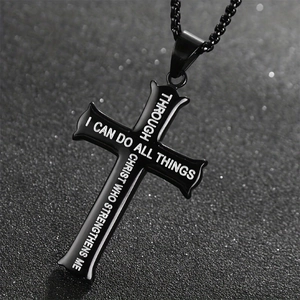 Macro shot of black cross pendant with engraved biblical text on dark textured background