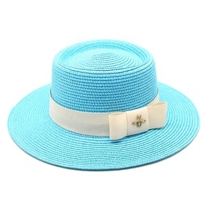 Detail view of sky blue boater hat with cream ribbon and gold bee metal ornament
