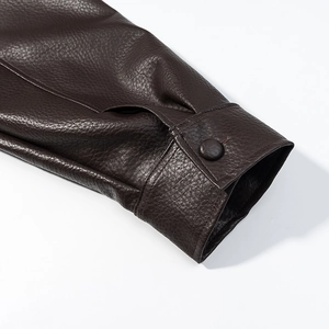 Detail of dark brown faux leather jacket cuff featuring lychee texture and round button