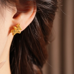 Detail of a gold-plated pegasus earring with crown and hammered texture on ear