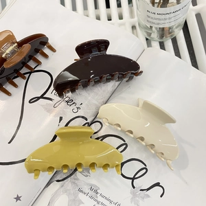 Detailaufnahme von großen Acetat-Haarklammern in Karamell, Beige und Braun auf einem Magazin