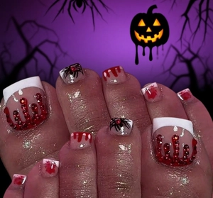 Macro detail of Halloween press-on toenails featuring red blood drips and spider nail art