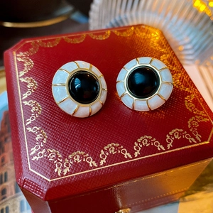 Close-up of vintage gold plated earrings with white enamel on a luxury jewelry box