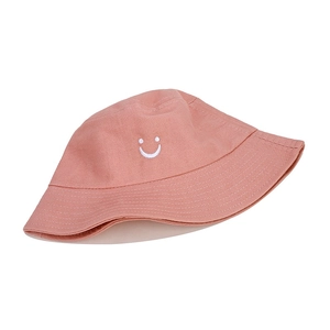 Detailed embroidery of a white smiley face on the front of a pink cotton bucket hat