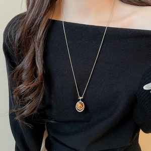 Detail view of model wearing a tiger eye stone pendant necklace with gold chain