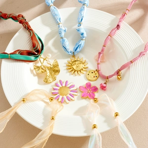Floral pendants on colorful fabric cords and organza ribbons in a ceramic plate