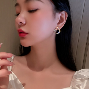 Close-up of gold-plated twisted hoop earrings with sparkling rhinestones on model