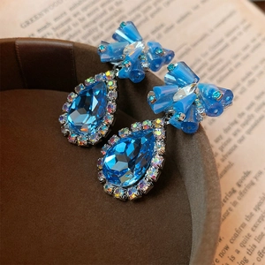 Detailed view of blue teardrop crystal earrings with rhinestones on a vintage book