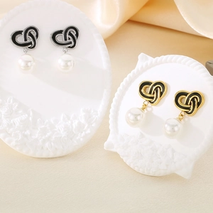 Detail of vintage heart-shaped knotted stainless steel earrings with hanging pearls
