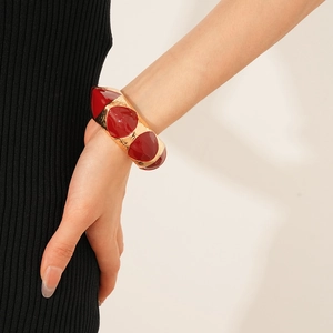 Detailed view of vintage wide gold bangle with red enamel teardrop inserts on wrist