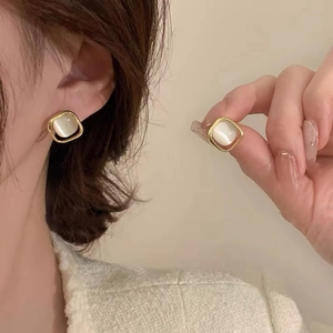 Boucles d'oreilles carrées en pierre œil de chat et cadre doré portées par un modèle