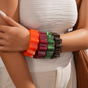 Close-up of four acrylic wavy bangle bracelets in orange, green, red and brown