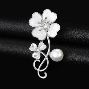 Macro shot of silver clover brooch with shell petals, crystal center and pearl drop detail