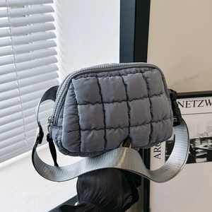 Detailed view of gray quilted crossbody bag with wide adjustable shoulder strap