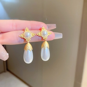 Detailed close-up of vintage style gold drop earrings with white pearls and luxury finish