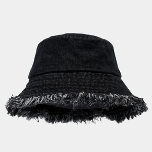 Detailed view of frayed raw edge tassels on black denim bucket hat with stitching
