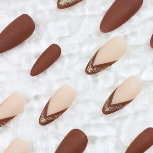 Detail of long almond press-on nails featuring brown matte and glitter French design