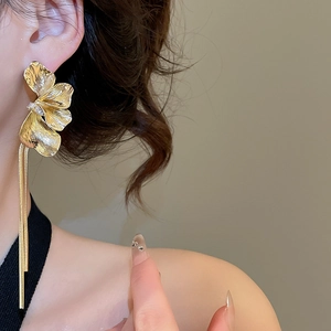 Gros plan sur des boucles d'oreilles pétales dorées avec de longs glands en métal