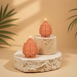 Terracotta beetle-shaped scented candles on travertine stone with palm leaf shadows