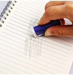 Close-up of 2B plastic eraser removing pencil marks on a lined notebook page