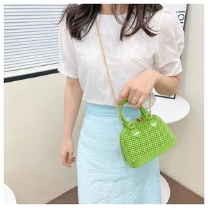 Green PVC jelly bag with gold chain strap shown on model with summer outfit