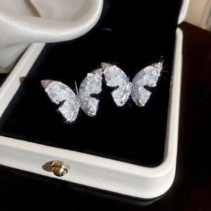 Macro detail of silver butterfly earrings with sparkling crystals on black velvet