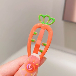 Close-up of cute orange carrot hair clip with green leaves for children's hair accessories