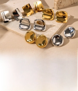 Close-up of geometric stainless steel stud earrings on a textured stone surface