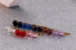 Macro detail of faceted crystal earrings in multiple colors with gold-tone hooks