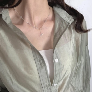 Close-up of minimalist 925 sterling silver T-bar necklace on a model wearing green shirt