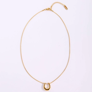 Macro shot of 18k gold plated horseshoe pendant with fine snake chain on white background