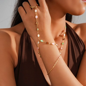 Detail shot of a golden hand chain featuring colorful resin gems on a model hand