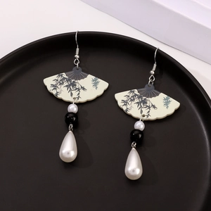 Detail of fan-shaped drop earrings with bamboo motif and elegant white teardrop pearl