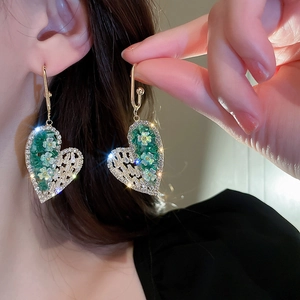 Close-up of golden butterfly earrings with green crystal and zircon on a model ear