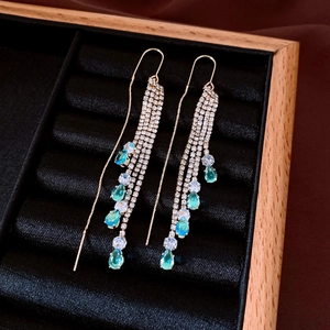 Macro view of teardrop crystal tassel earrings with sparkling rhinestones on velvet