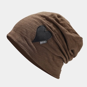 Close-up of brown knitted beanie showing fine rib texture and leather heart patch