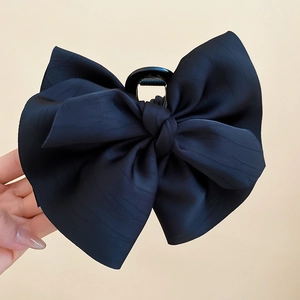 Dettaglio di un grande fermaglio per capelli con fiocco di raso nero e texture in tessuto