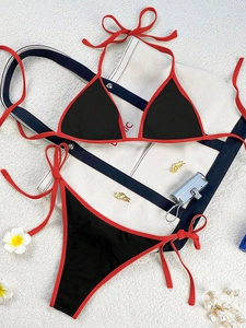 Flat lay of a two-piece bikini set with black fabric and red contrast binding details