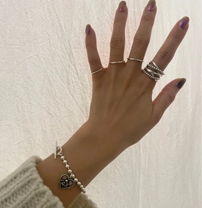 Detail of vintage 925 sterling silver layered rings and heart angel pendant bracelet
