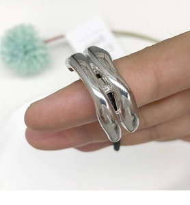 Macro detail of silver liquid metal ring with irregular wave design and mirror finish