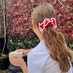 Detail of red and pink crochet scrunchie worn on ponytail in an outdoor setting