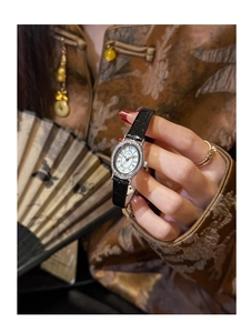 Macro shot of oval rhinestone-set watch bezel with vintage leather strap texture