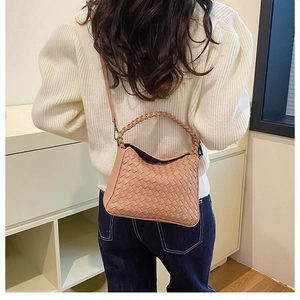 Detailed view of dust pink woven leather shoulder bag with a crossbody strap and top handle