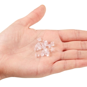 Macro shot of transparent silicone earring backs displayed on an open palm with white background