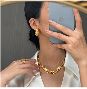Detailed view of model wearing a textured gold geometric jewelry set with necklace and earrings