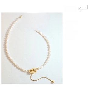Detailed view of freshwater pearls and K18 engraved gold tag on Roman numeral necklace