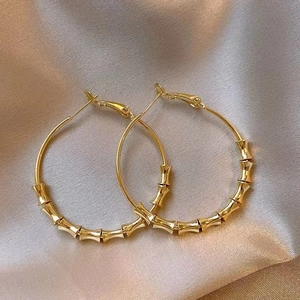 Macro shot of large gold hoop earrings with bamboo texture on a satin fabric background