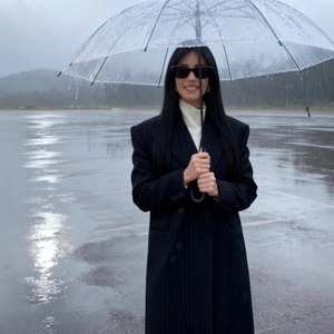 Women's black pinstripe double-breasted coat with tailored waist and a clear umbrella