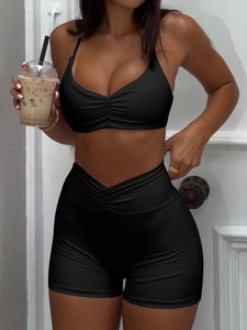 Detail eines schwarzen Sport-Sets mit V-Ausschnitt, gerafftem Top und High-Waist-Cross-Shorts