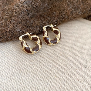 Detail of gold hoop earrings with brown enamel spots and sparkling crystal accents